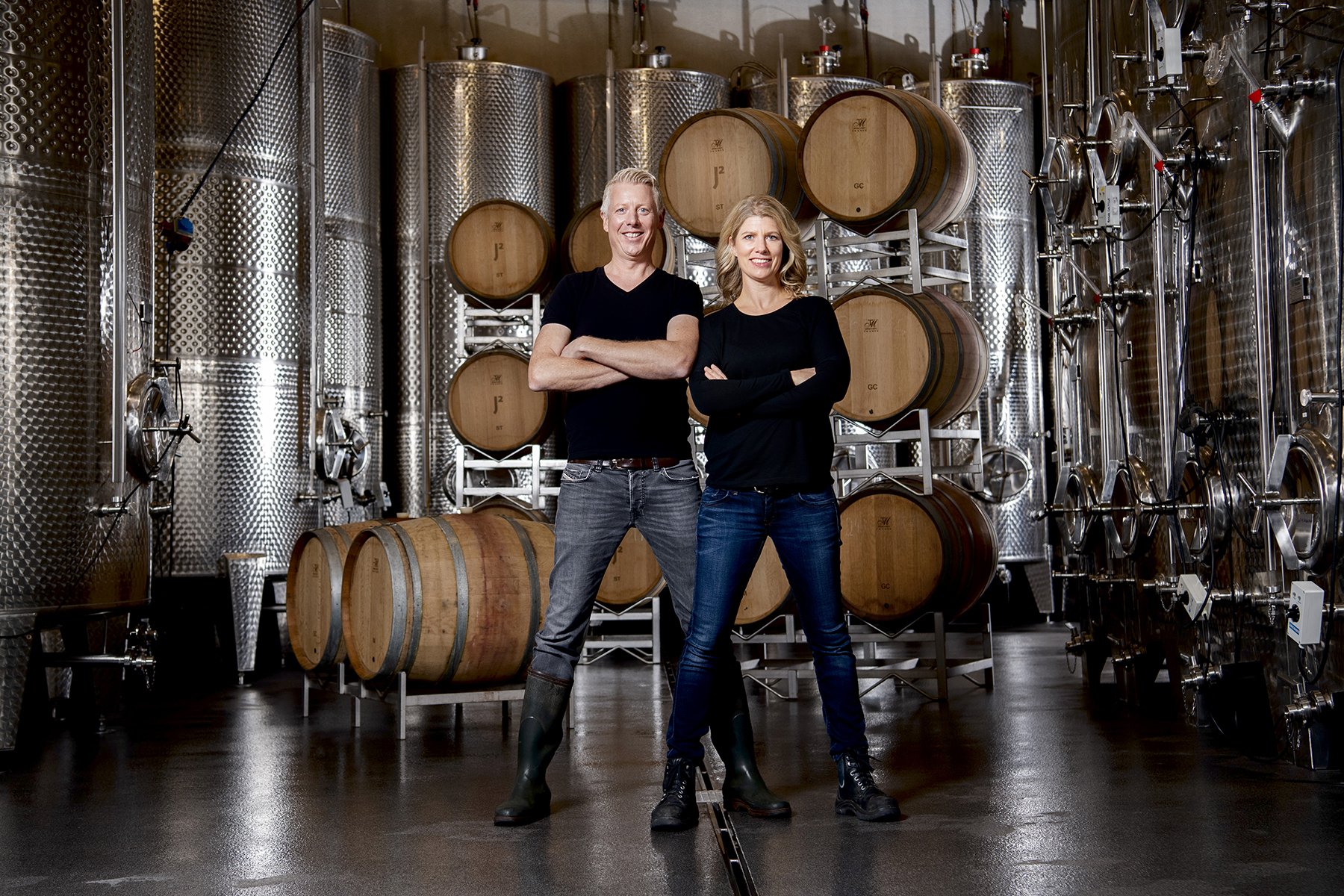 Portät eines Winzerpaares zwischen Fässern im Keller.