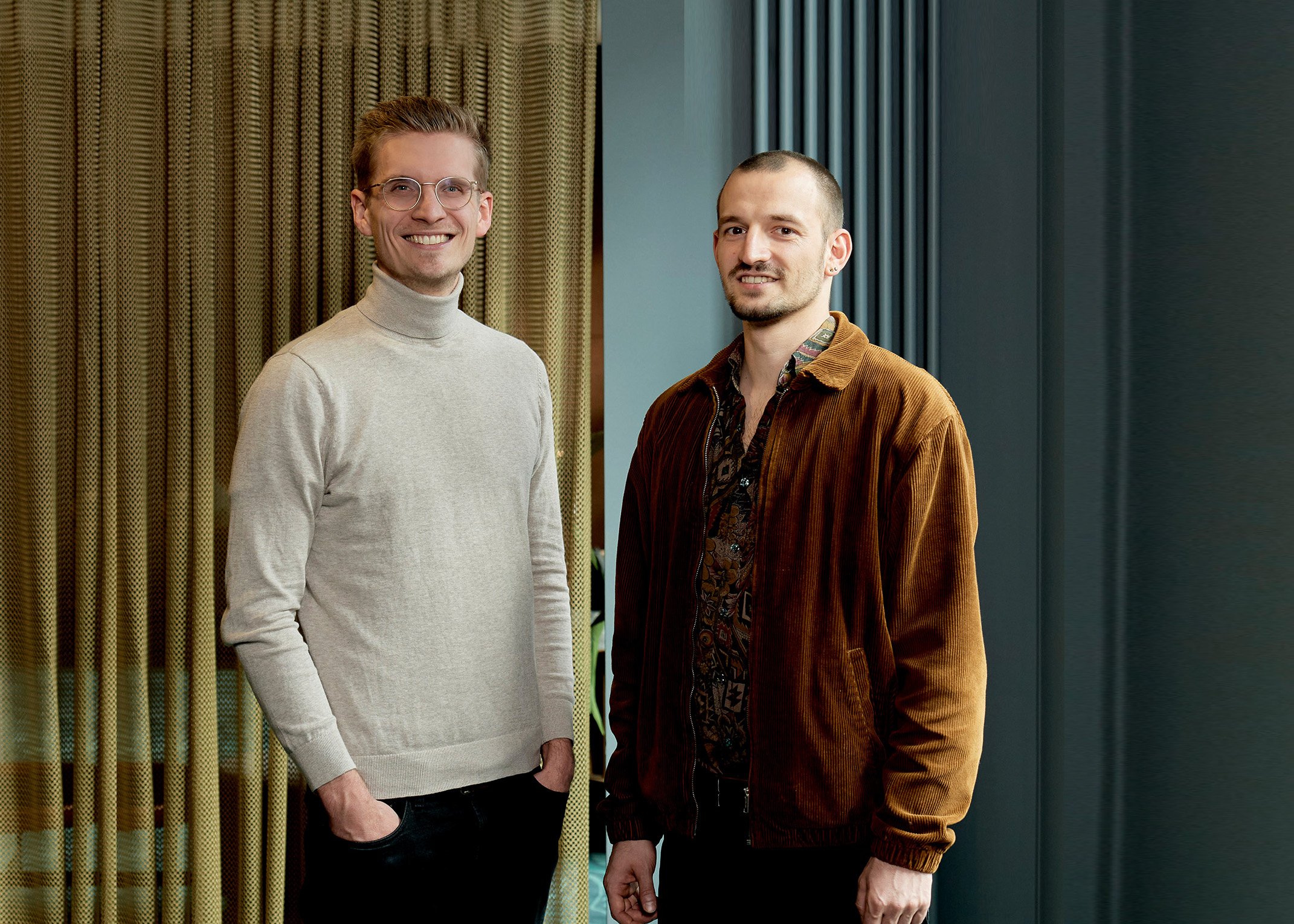 Portraitfoto von zwei jungen Männern aus der Startup Szene stehen in einem Berliner Hotel und schauen freundlich und direkt in die Kamera